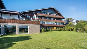 A multi-story hotel with balconies, a grassy lawn, and a clear blue sky. - Holiday Apartment 'Time 2 Sea' with Shared Garden, Balcony and Wi-Fi (Scharbeutz)