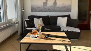 Uma sala de estar com sofá, mesa de centro, pintura de veados e radiador.