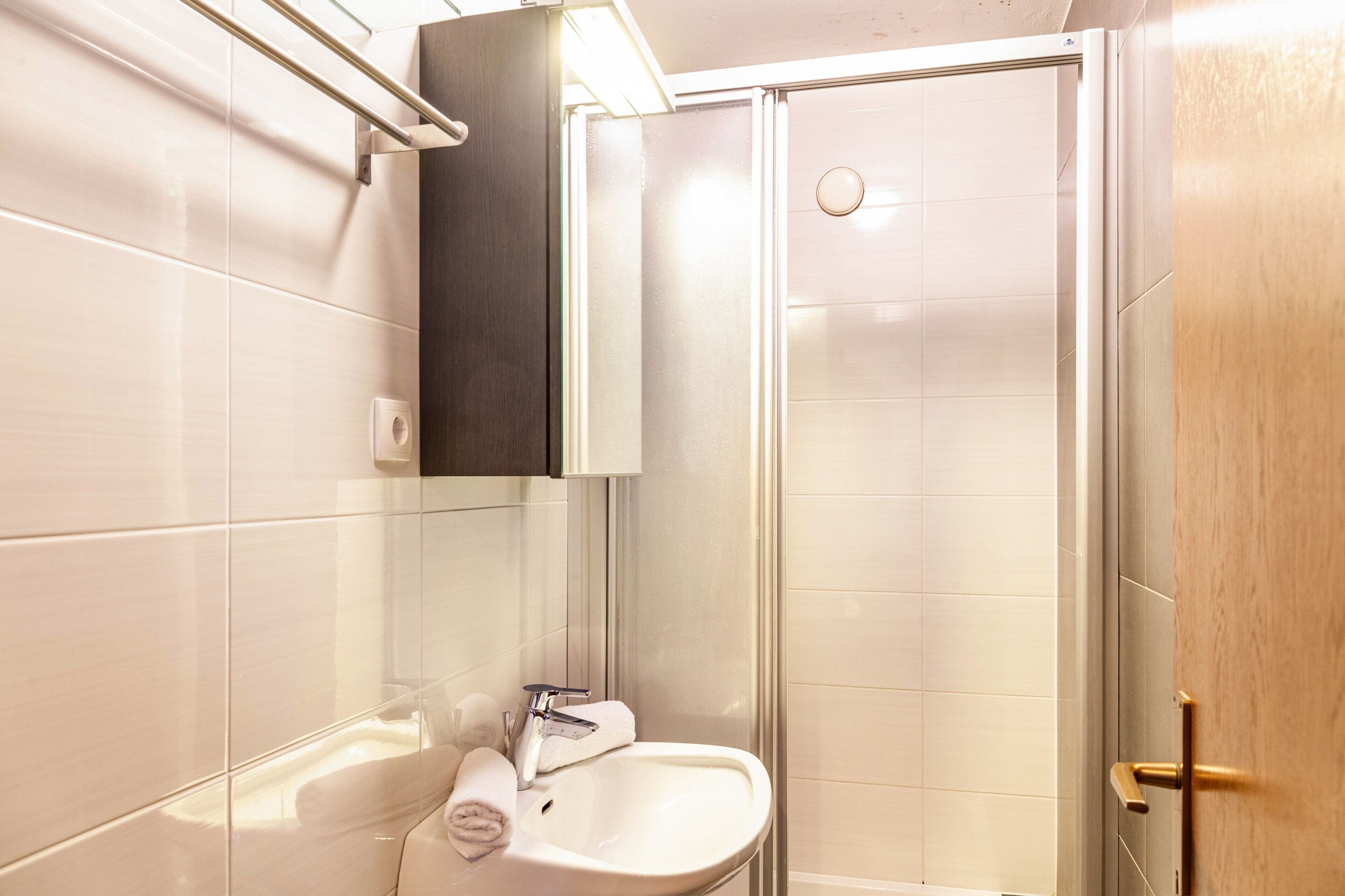A bathroom with a white sink, a towel, and a glass shower enclosure.