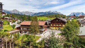 Un pueblo de montaña con casas de madera tradicionales, una calle principal y vistas de las montañas circundantes.