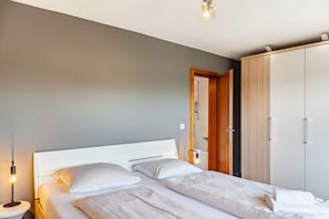 Una camera da letto con un letto, una lampada da comodino, un armadio e una porta che dà su un bagno.