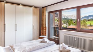 Un dormitorio con cama, armario, silla, radiador y ventana con vistas a la montaña.