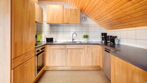 A kitchen with wooden cabinets, a sink, a clock, and a potted plant. - Apartment 'Haus Bross' with Balcony and Wi-Fi (Hayingen)