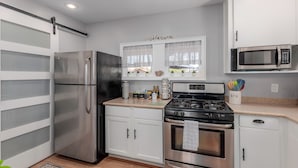 A modern kitchen with stainless steel appliances, white cabinetry, and a window with a view. - Charming Bungalow in the heart of Phoenix/Biltmore area.  (Phoenix)