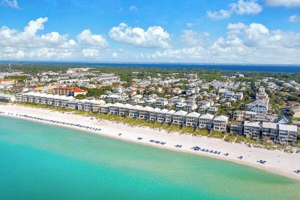 A coastal resort with beachfront villas, a sandy beach, and a clear view of the ocean.