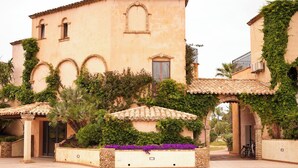 Un edificio con ventanas arqueadas, tejado de tejas y un jardín con flores moradas.