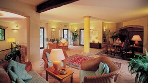 A spacious lobby with wicker furniture, a central column, and a reception desk.