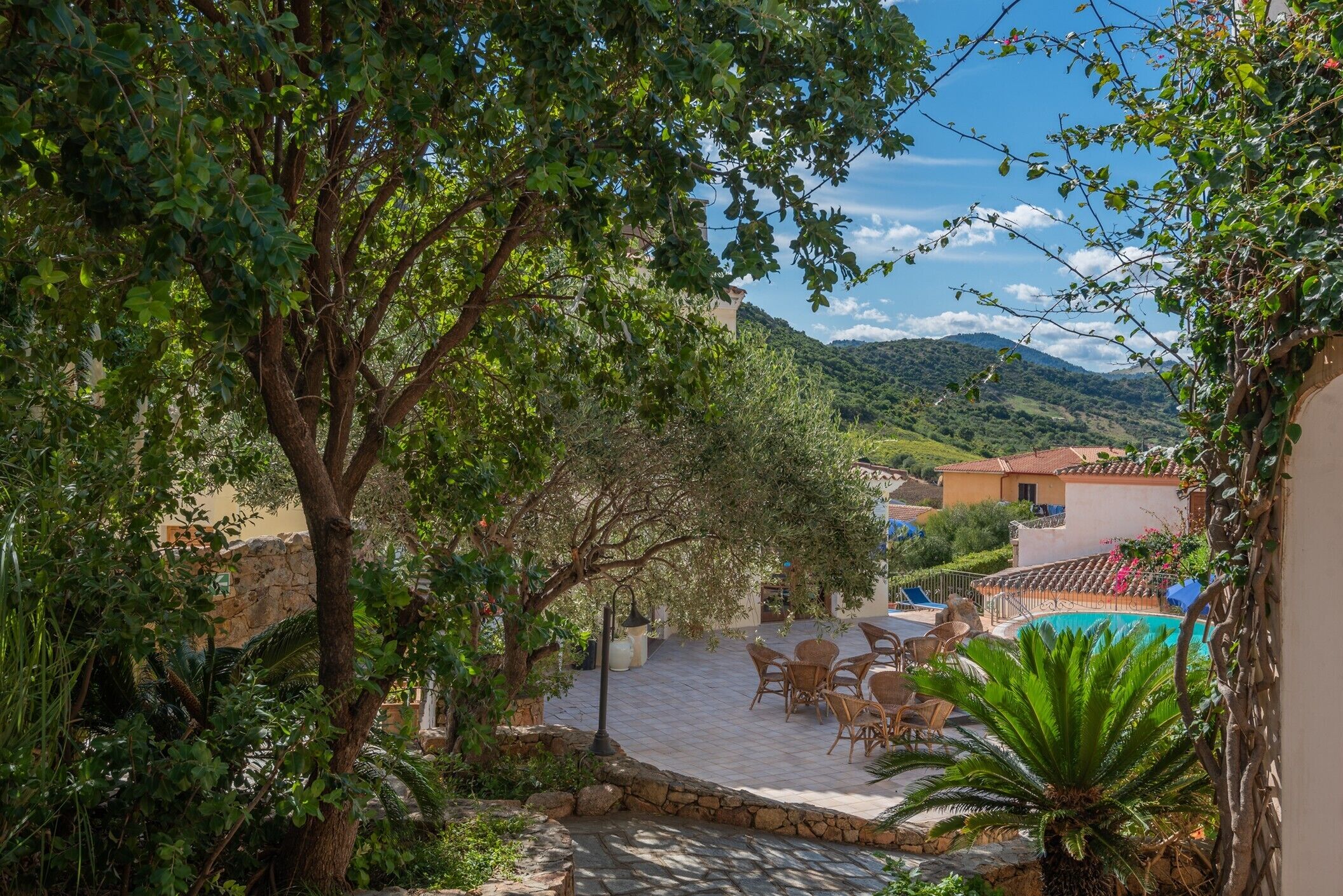 Un patio con suelo de piedra, mobiliario exterior y una piscina.