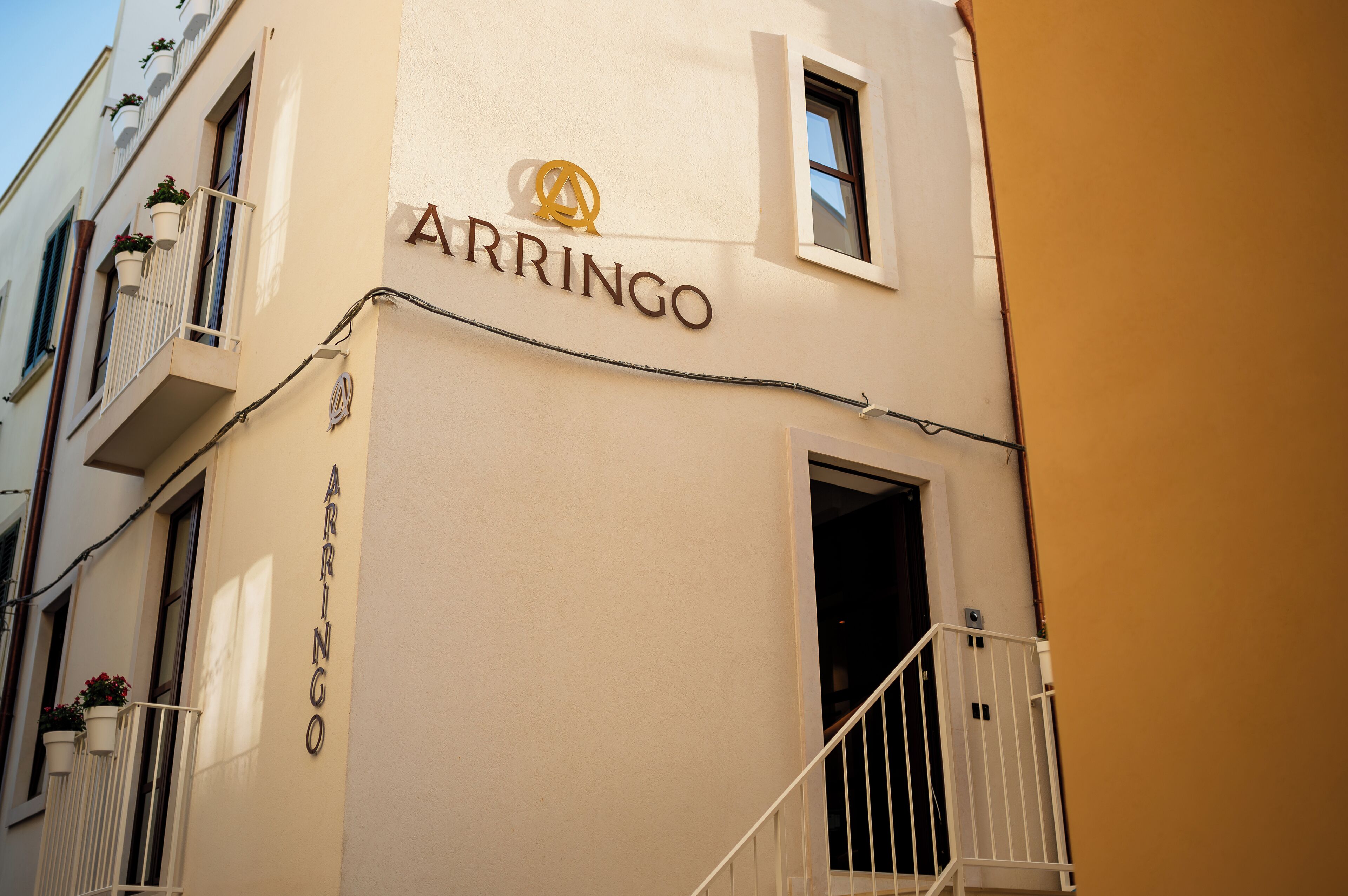Ein Gebäude mit dem Schild "ARRINGO" und einem Balkon mit Blumentöpfen.