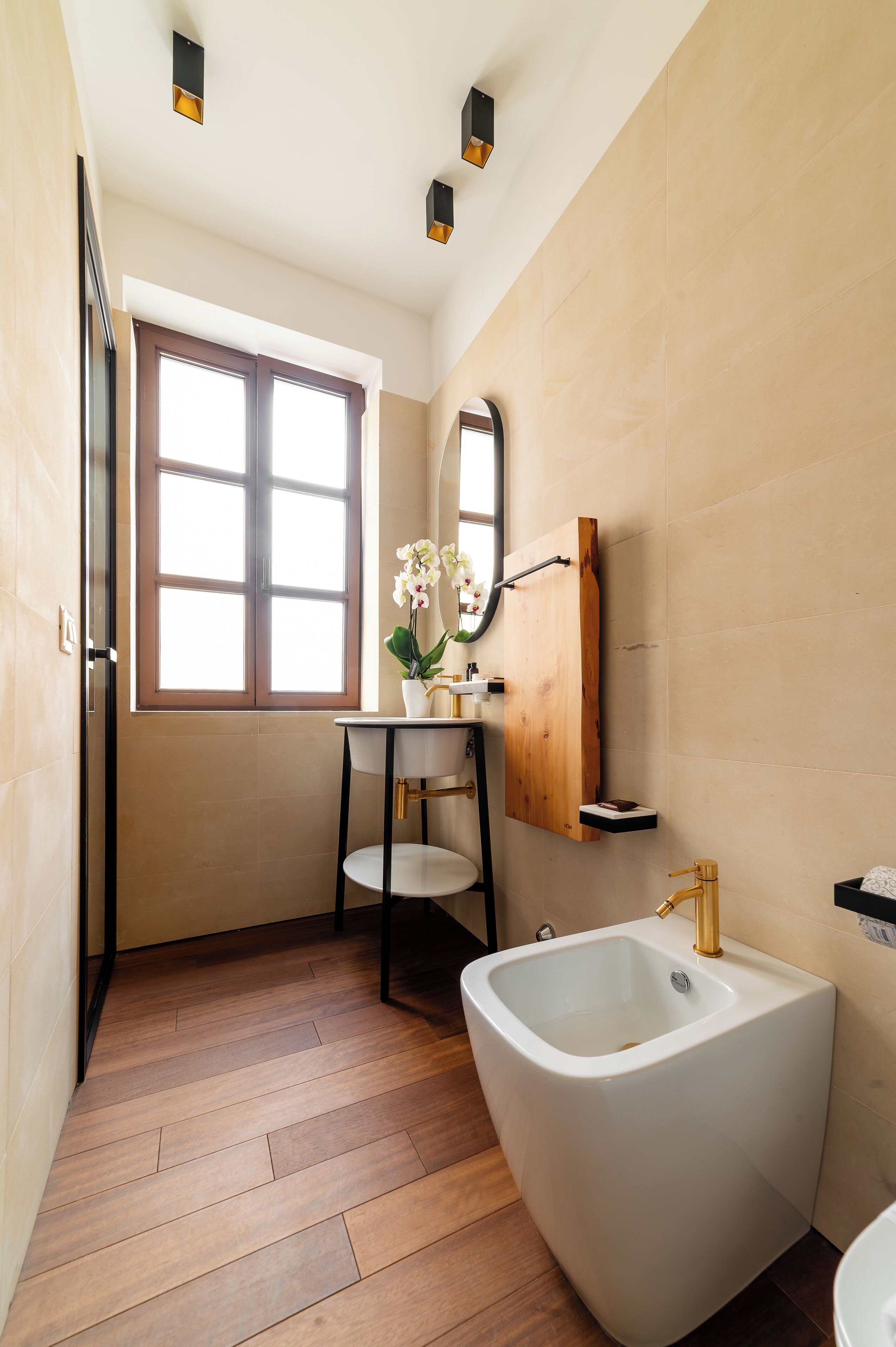 Een moderne badkamer met een vrijstaand bad, een klein wastafeltje met spiegel en een raam voor natuurlijk licht.
