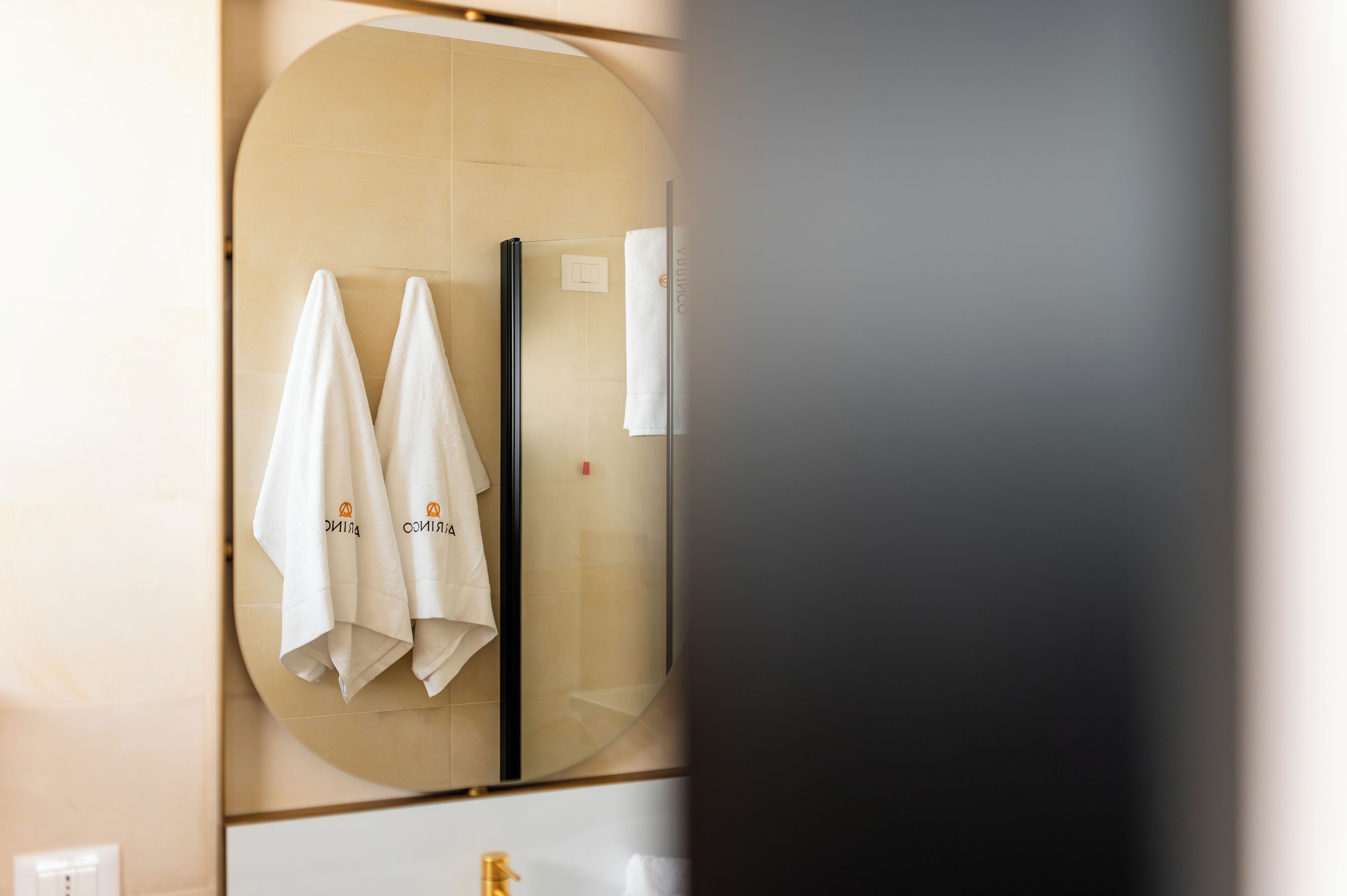 A bathroom with two towels hanging on a towel rack, a mirror, and a sink with a gold faucet.