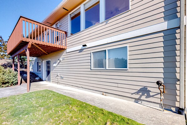 A two-story house with a wooden deck and a small window. - Peek-a-boo ocean view home with in-law suite, fireplace, & outdoor space (Coupeville)