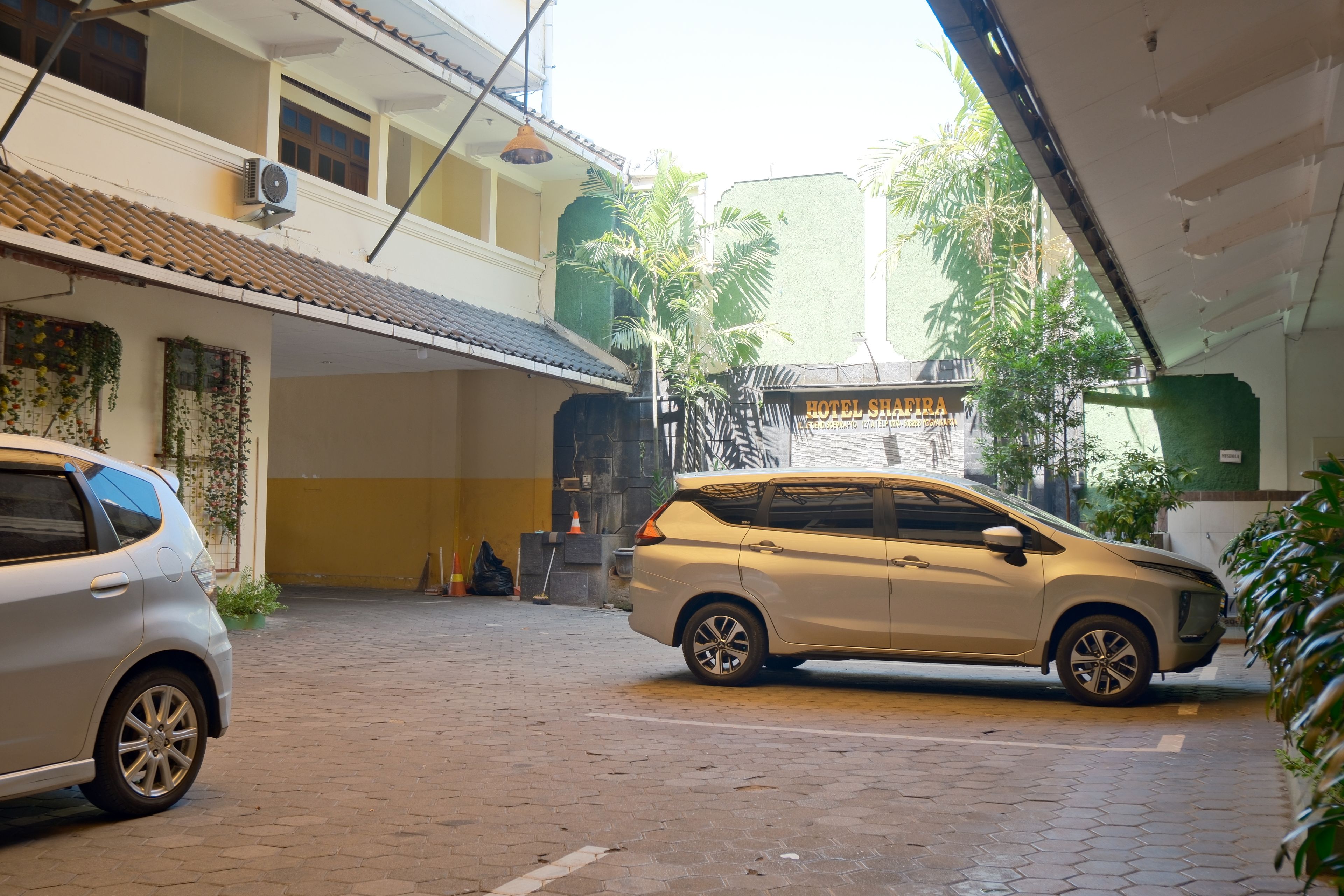 Un hotel con parcheggio coperto, una targa e un'auto parcheggiata in primo piano.