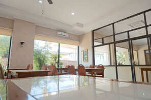A conference room with a large table and chairs, large windows, and an air conditioning unit on the ceiling. - Shafira Hotel Yogyakarta (Yogyakarta)