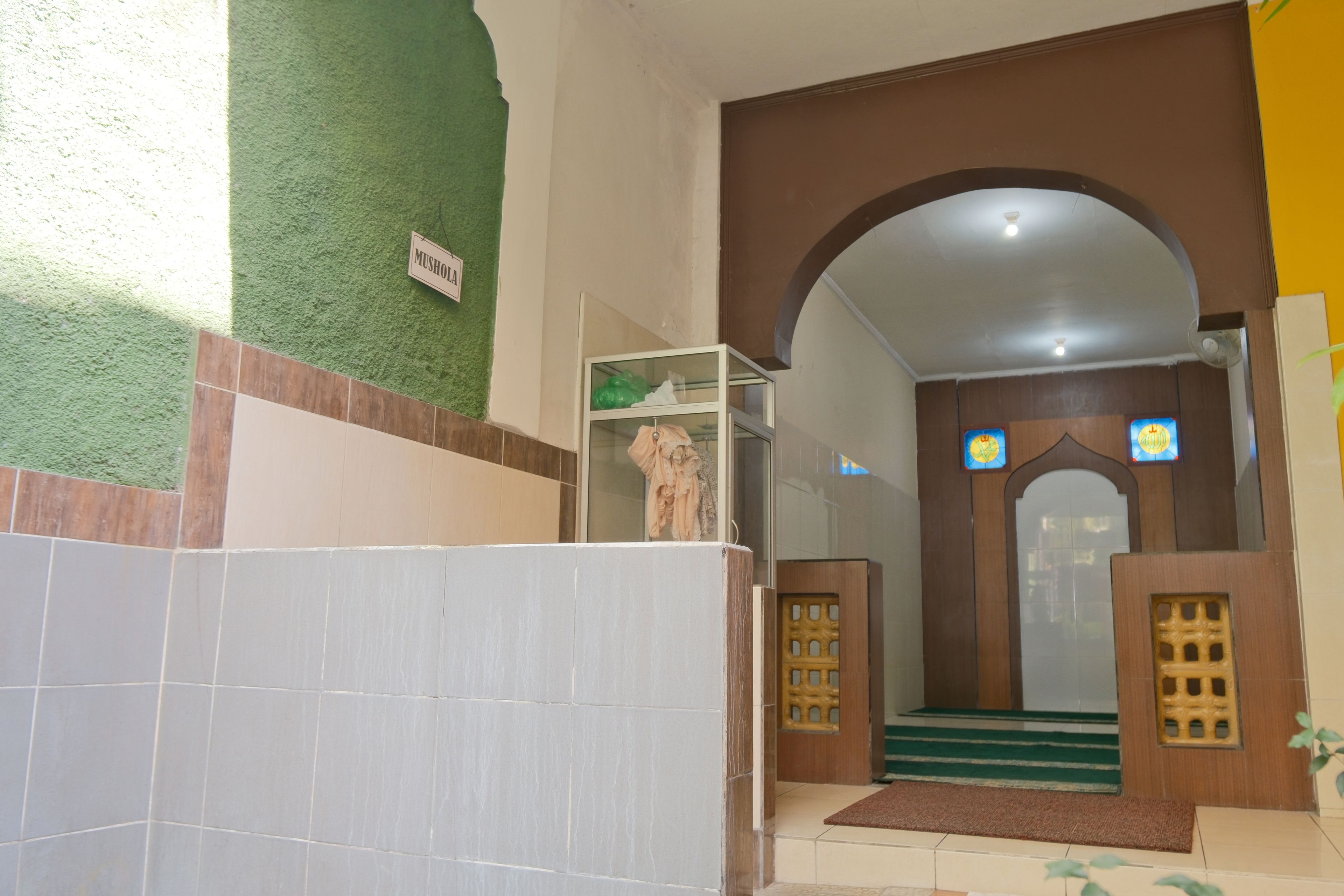 Entrada de hotel con pared verde, piso de baldosas y un letrero que dice 'MUSHROOM'.