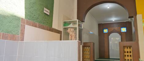 Entrada de hotel con pared verde, piso de baldosas y un letrero que dice 'MUSHROOM'.