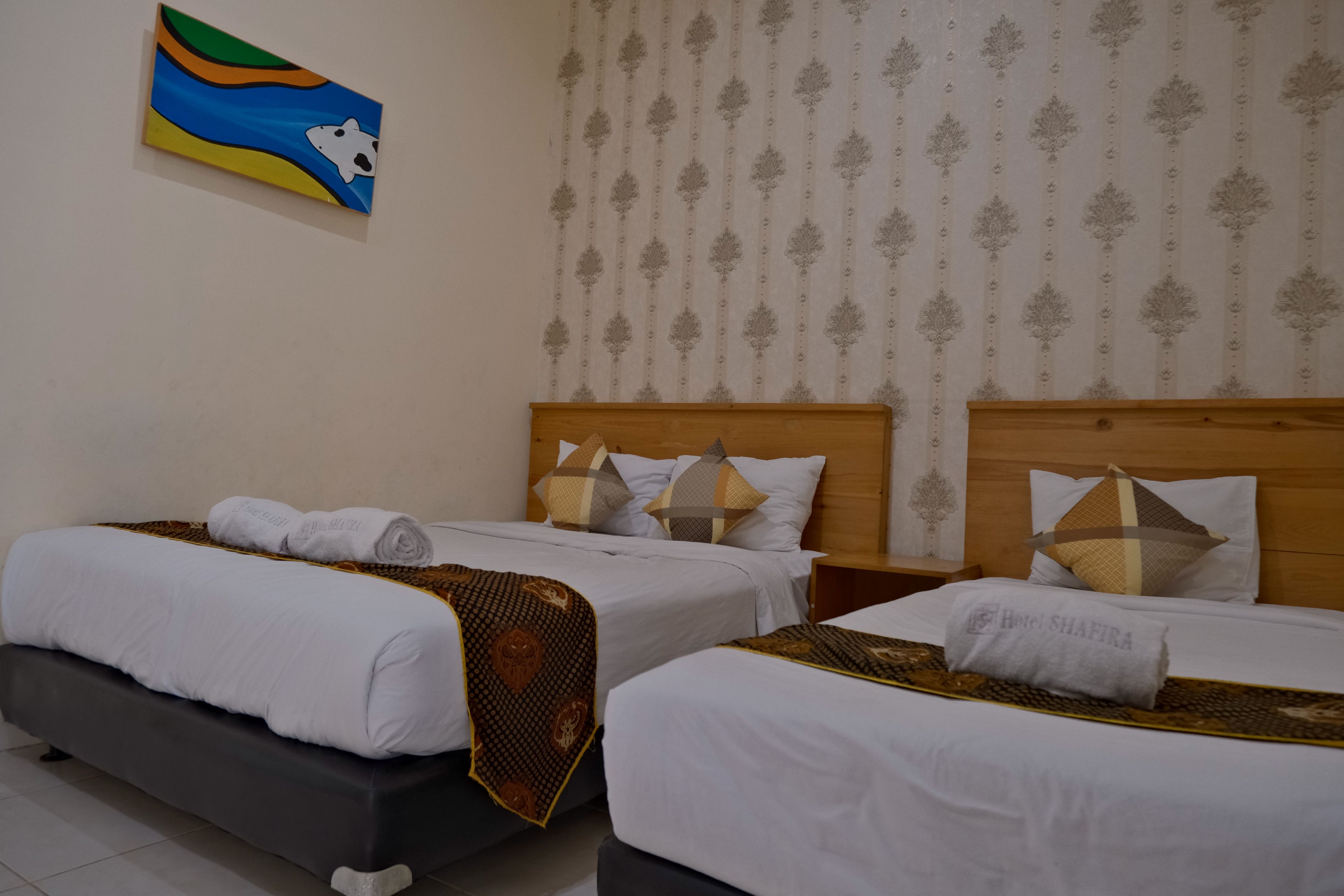 Une chambre d’hôtel avec deux lits, une tête de lit en bois et une décoration murale.