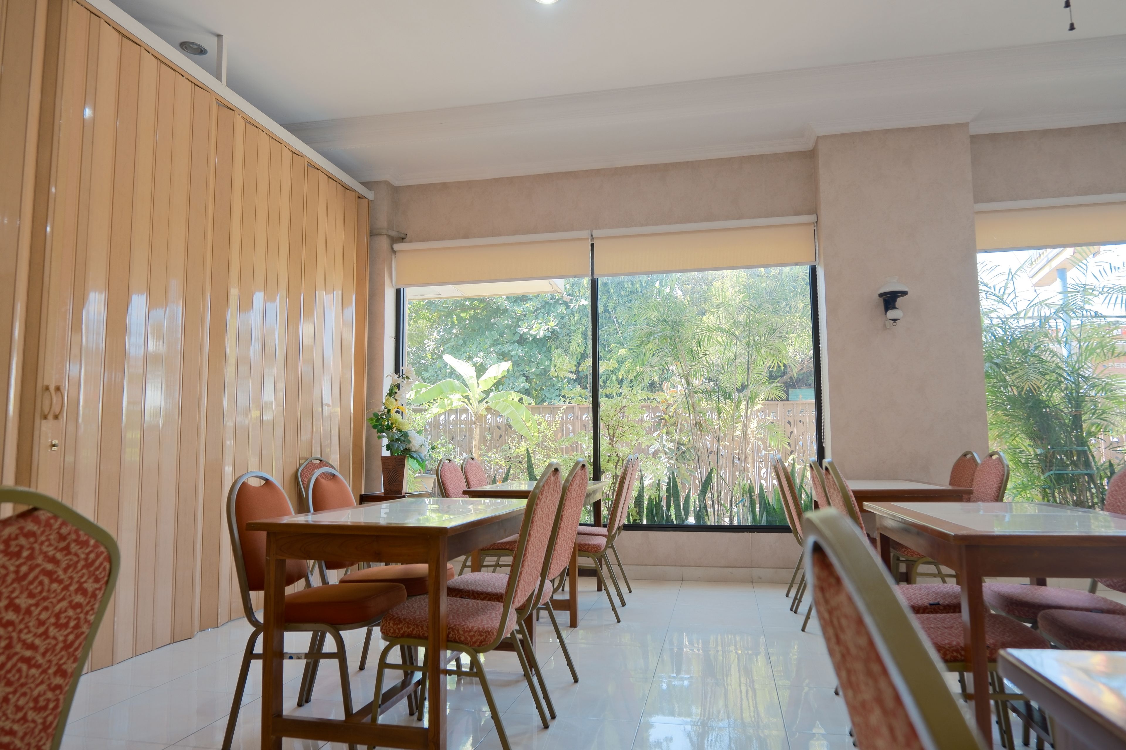 A dining area with wooden panel walls, large windows, and a view of greenery outside.