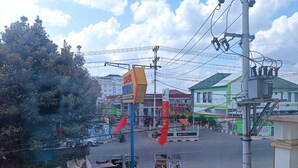 A street view with a hotel sign, a green building, and a parked car. - Shafira Hotel Yogyakarta (Yogyakarta)