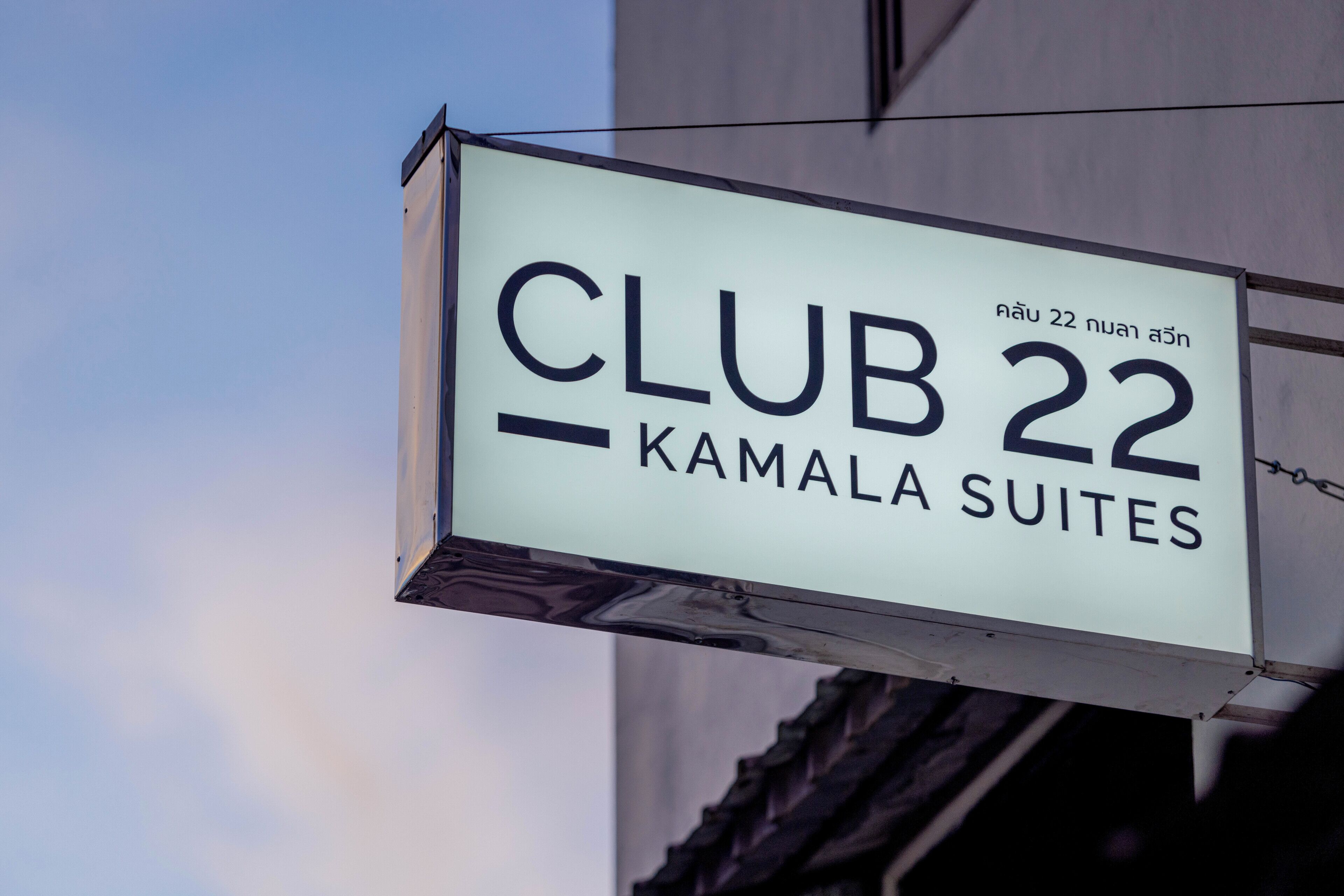 A sign for 'CLUB 22 Kamala Suites' with a clear, rectangular shape and bold lettering.