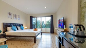 A hotel room with a bed, a TV, a desk with a coffee maker, and a view of the outdoors. - Club 22 Kamala Suites (Kamala)