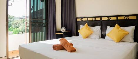 Habitación de hotel con cama, mesita de noche y vistas al verde exterior.