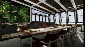 A modern dining area with a long wooden table, brown chairs, and a green wall with plants. - Funhome Bo Song Set Apartment Ha Noi (Hanoi)