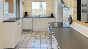 Eine moderne Küche mit weißen Schränken, einer schwarzen Arbeitsplatte und einem Fenster mit Blick auf Bäume.