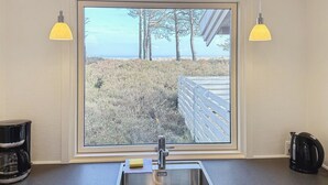 Eine Küche mit einem großen Fenster, einem Spülbecken und zwei Pendelleuchten.
