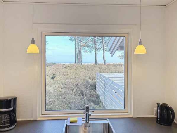 A kitchen with a large window, a sink, and two pendant lights.