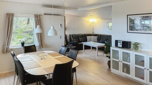 Ein modernes Wohnzimmer mit Essbereich, einer Couch, einem Couchtisch und einer Vitrine mit Glastüren.