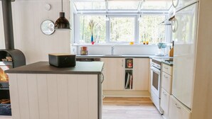 Ett modernt kök med en central köksö, inbyggda vitvaror och ett stort fönster som släpper in naturligt ljus.