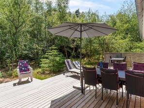 Eine Terrasse im Freien mit Tisch und Stühlen, umgeben von üppigem Grün.
