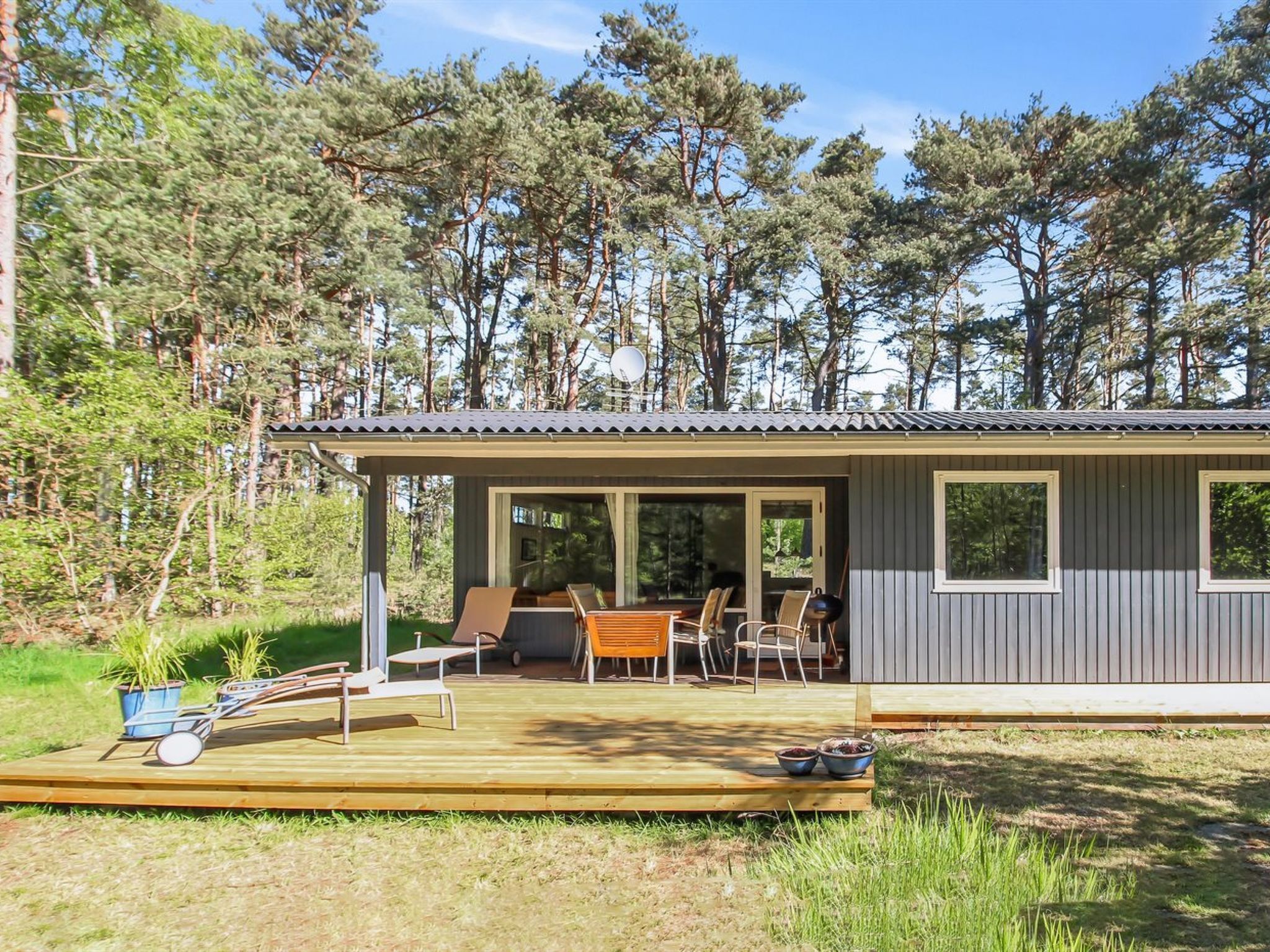 A cabin with a deck, outdoor seating, and a view of the surrounding forest.