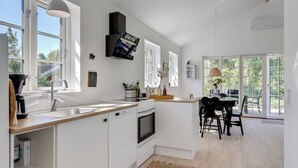 Ett modernt kök med vita skåp, en inbyggd ugn och en matplats med bord och stolar.