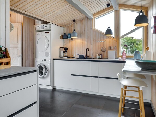 Une cuisine moderne dotée d’appareils électroménagers intégrés, d’éléments décoratifs en bois et de grandes fenêtres.