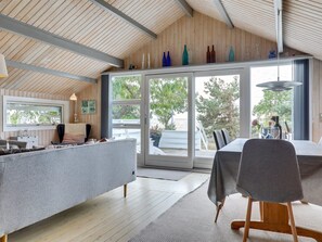 Une cuisine moderne dotée d’un grand îlot central, d’un coin repas avec une table et des chaises, et offrant une vue sur l’extérieur grâce à de grandes portes coulissantes.