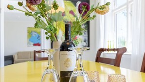 Ett matbord med en flaska Castano Col-vin, två vinglas och två dekorativa glasvaser.