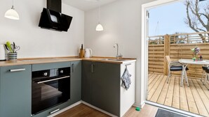 A modern kitchen with a built-in oven, a sink, and a dining area with a table and chairs. - "Kiana" - 250m from the sea by Interhome (Nexø)