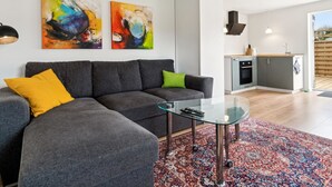 A modern living room with a grey sectional sofa, a glass coffee table, and two abstract paintings on the wall. - "Kiana" - 250m from the sea by Interhome (Nexø)