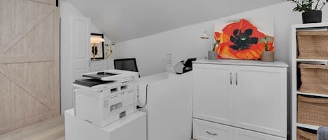 A compact room with a desk, printer, and cabinets.