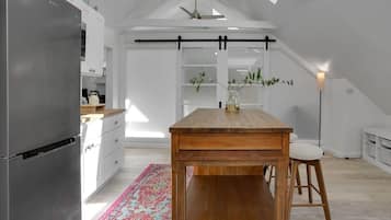 Una cocina moderna con una mesa de madera, armarios blancos y un tapete colorido.