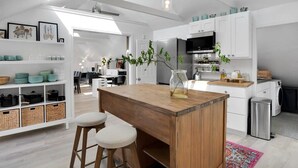 A modern kitchen with white cabinetry, a wooden island with stools, and a stainless steel refrigerator. - Capitola Village Work-Live Loft - Pet Friendly (Capitola)