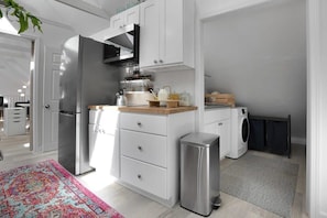 Una cocina moderna con armarios blancos, electrodomésticos de acero inoxidable y encimera de madera.