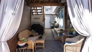 A covered patio area with wicker furniture, a barbecue grill, and a welcome sign. - Capitola Village Hideaway Bungalow - Pet friendly! (Capitola)