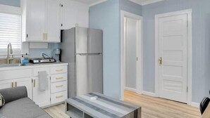 Une cuisine de taille réduite avec des meubles blancs, un réfrigérateur et un plan de travail doté d’un évier.