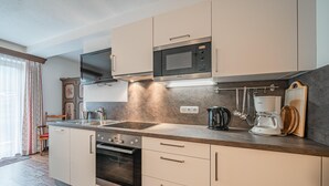 Una cocina moderna con horno empotrado, microondas y cafetera.