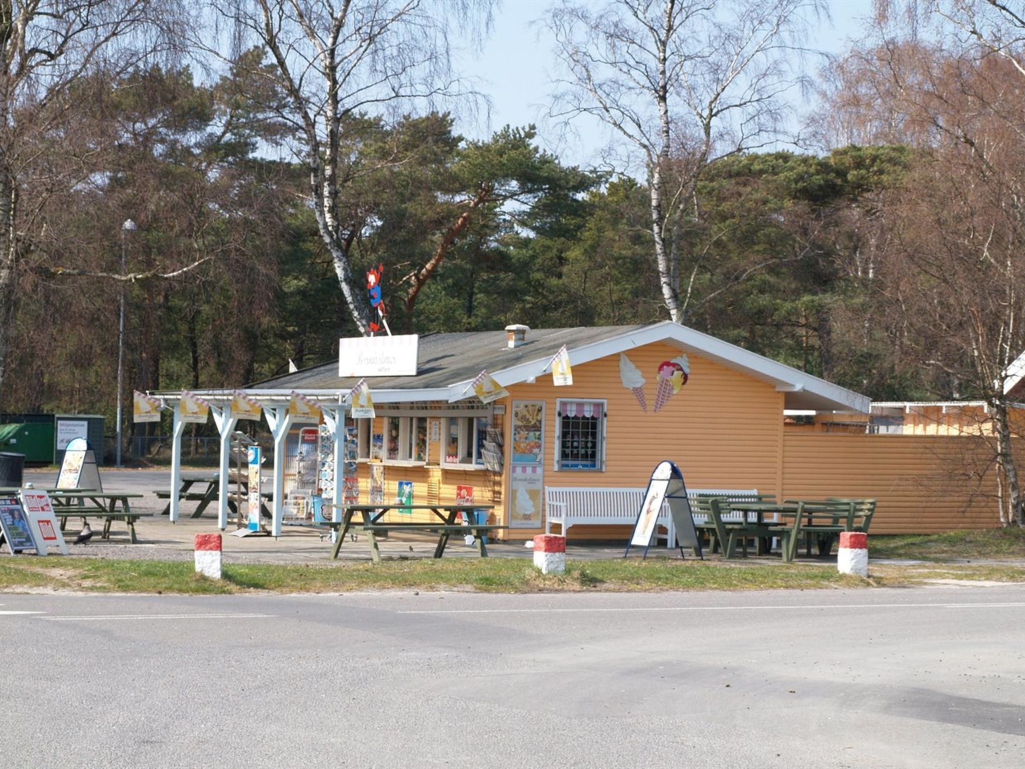 A small, single-story building with a sloped roof, a covered outdoor seating area, and a picnic table.