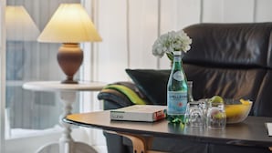 Une pièce avec une table, une bouteille d’eau S. Pellegrino, un saladier de fruits et une boîte de Ludo.