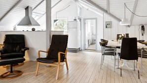 Un loft spacieux avec de hauts plafonds, un coin repas doté de chaises modernes et une grande fenêtre laissant entrer la lumière naturelle.
